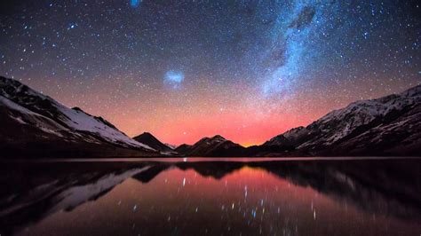 the night sky is filled with stars above mountains and water, as seen ...