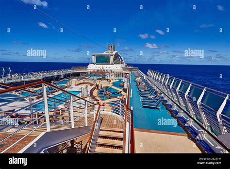 A cruise ship view of the top deck with blue water and cloudy skies ...