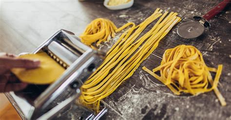 Preparing home made pasta with pasta maker on wooden table. photo ...