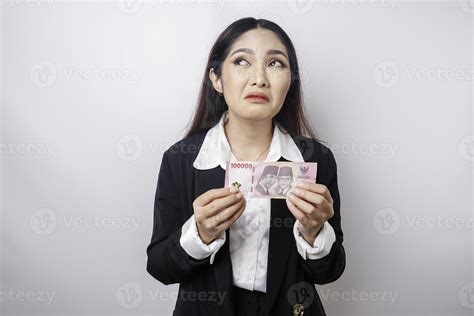 A thoughtful young woman is wearing black suit and holding cash money ...