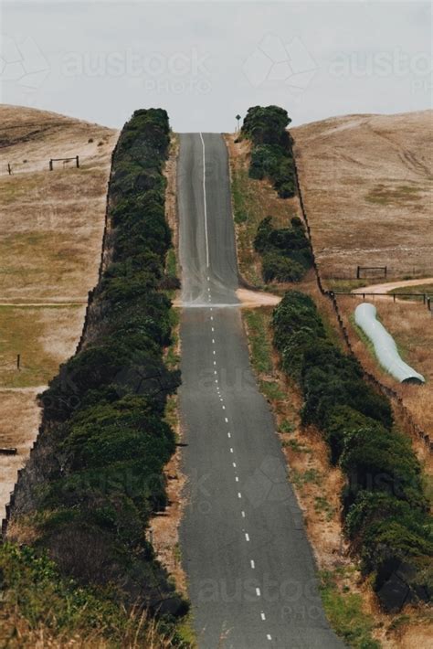 Image of A steep road between farming land - Austockphoto