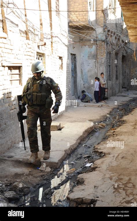 An Iraqi soldier moves down an alleyway while local Iraqi children look ...