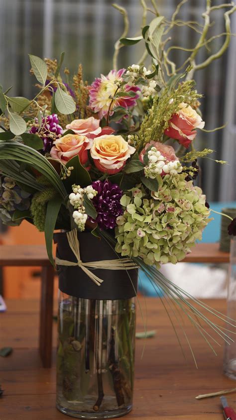 a vase filled with lots of flowers on top of a wooden table