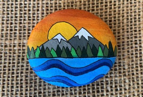 a painted rock sitting on top of a burlock covered canvas background ...