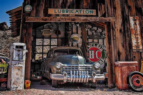 an old car is parked in front of a building with signs and gas pumps on it