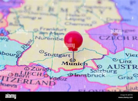 Round red thumb tack pinched through city of Munich on Germany map ...