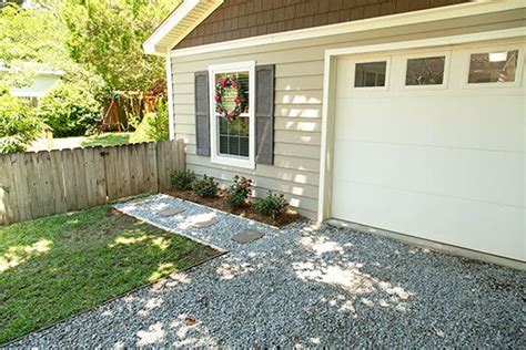 a small house with a gravel driveway in front of it and a white garage door