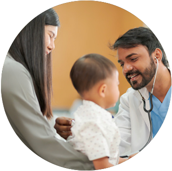 A tan middle-aged doctor uses a stethoscope on a baby as the baby sits on his mother’s lap.