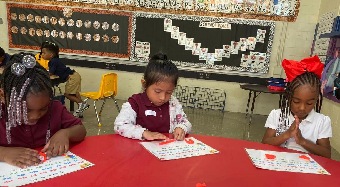 Children sitting at a table in a classroom working hard on class work