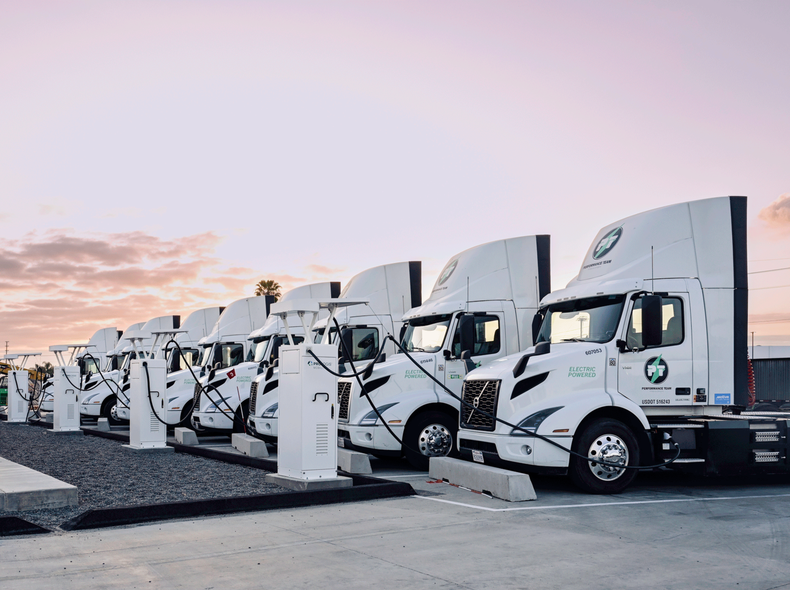 Electric semi-trucks charging at dusk