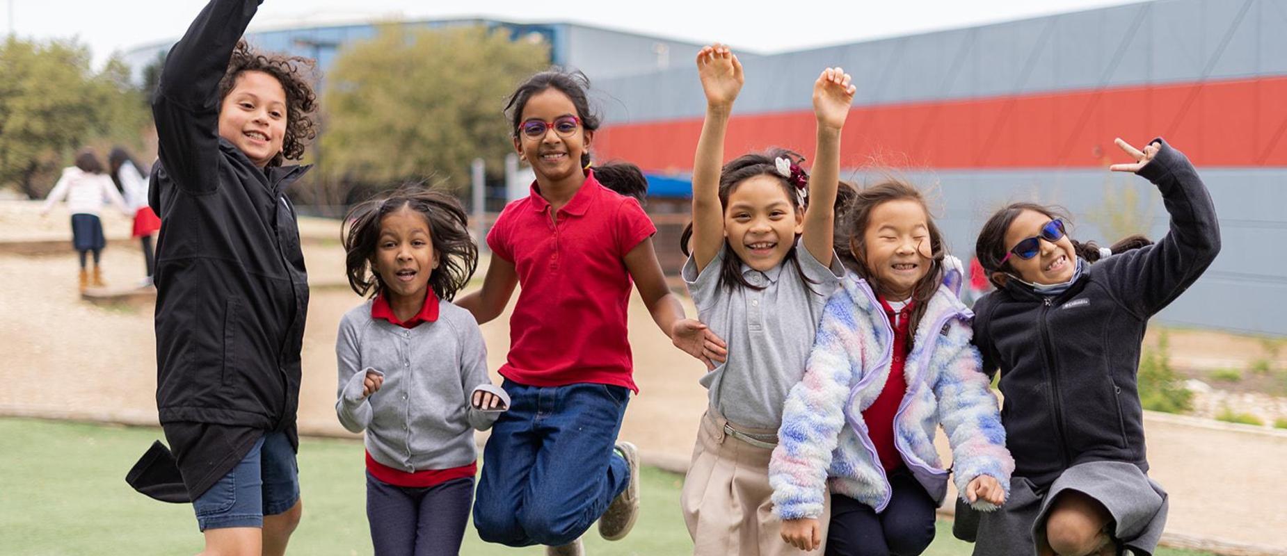 Five students jump for joy in the playground