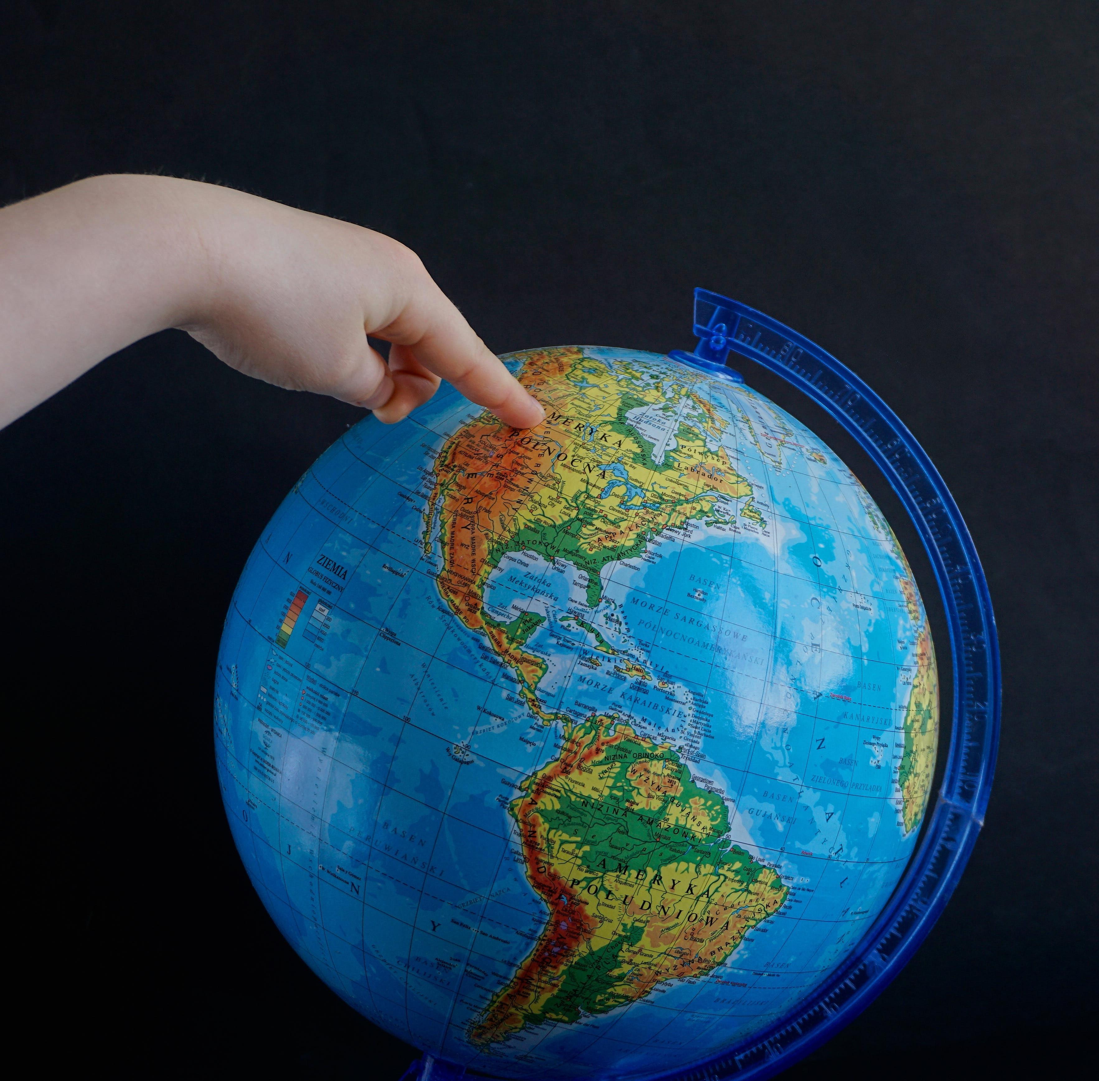 child pointing at a globe