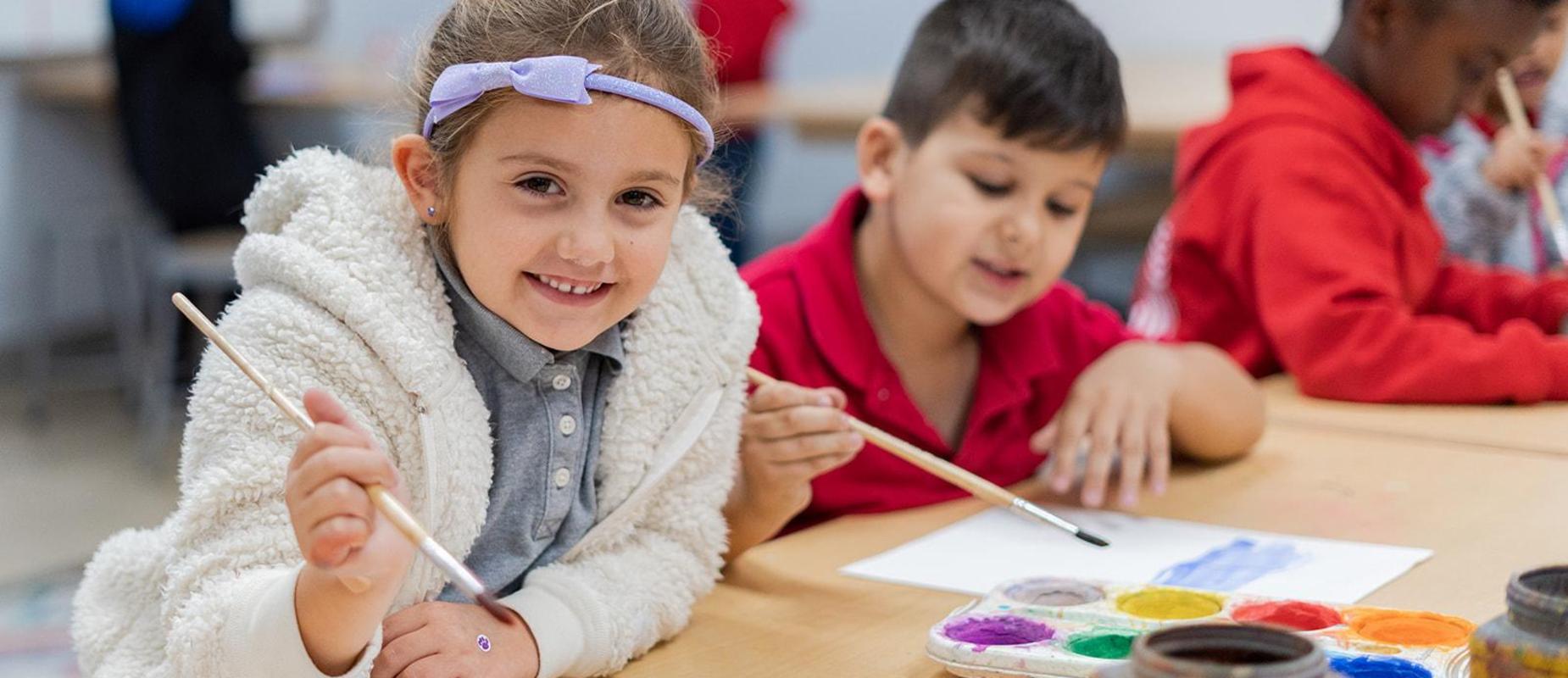 Primary students paint on white paper