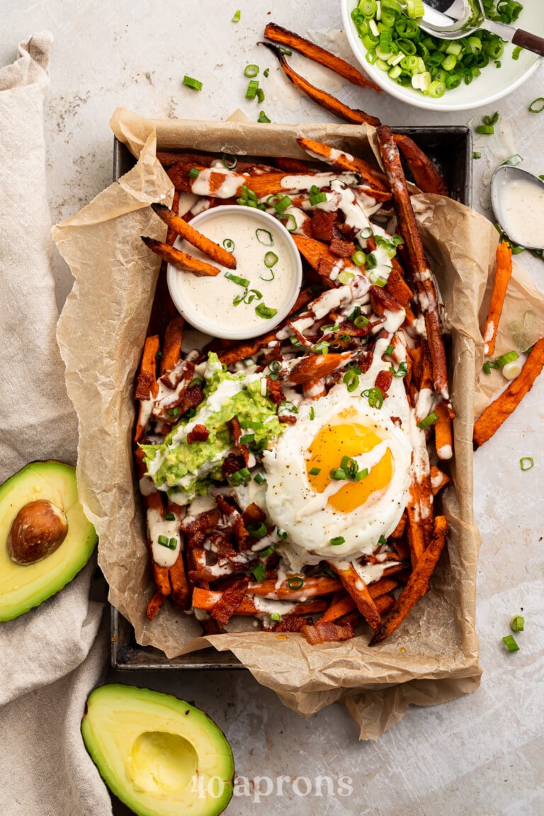 Whole30 Loaded Sweet Potato Fries in a parchment paper lined dish, shot from overhead