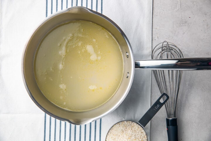 Overhead view a medium saucepan with salted water and melted butter.