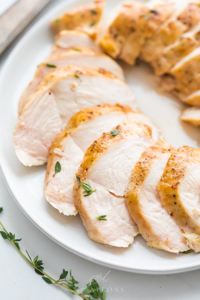 Chicken breast medallions arranged on a white plate on a marble counter