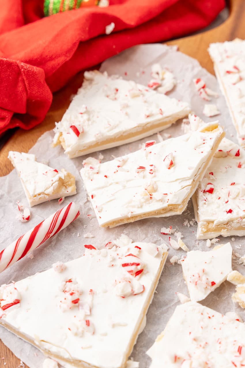 peppermint sugar cookie bark pieces on a parchment paper covered wooden cutting board