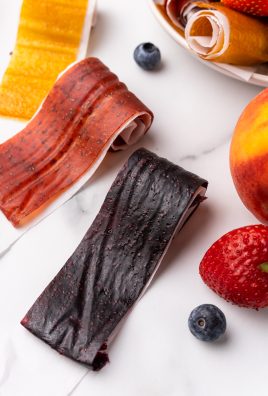 homemade fruit roll ups on a marble countertop next to fresh fruits