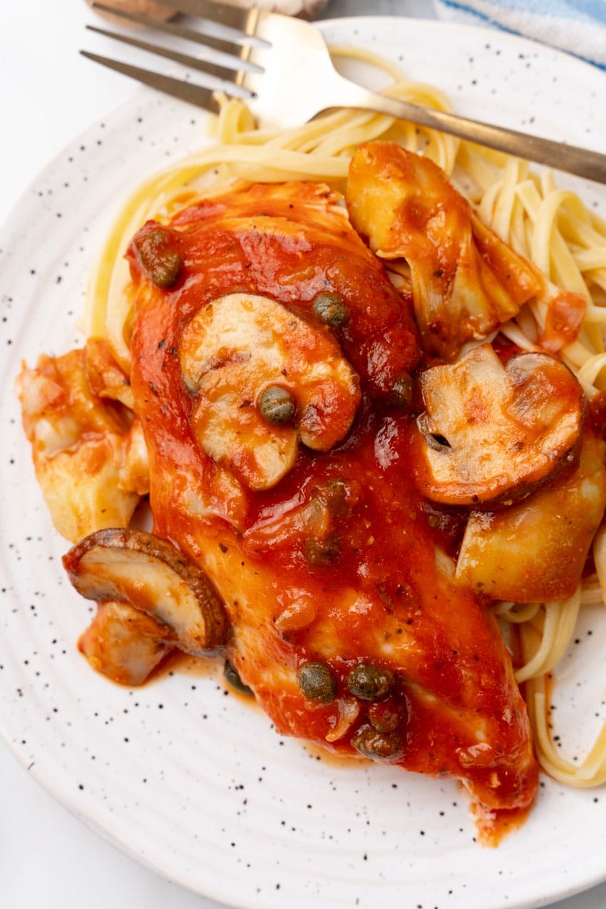 easy tuscan chicken on a white plate with a gold fork on the side