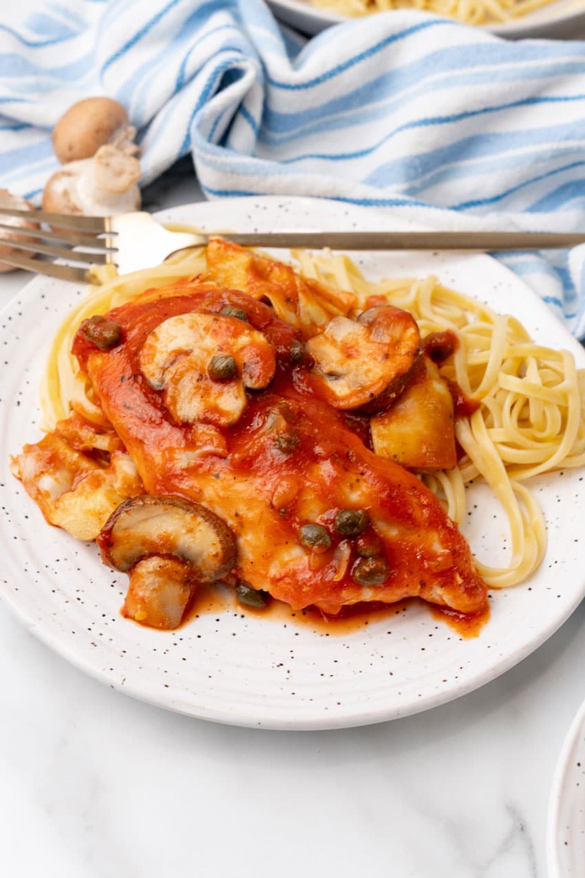 easy tuscan chicken on a white plate with a gold fork on the side