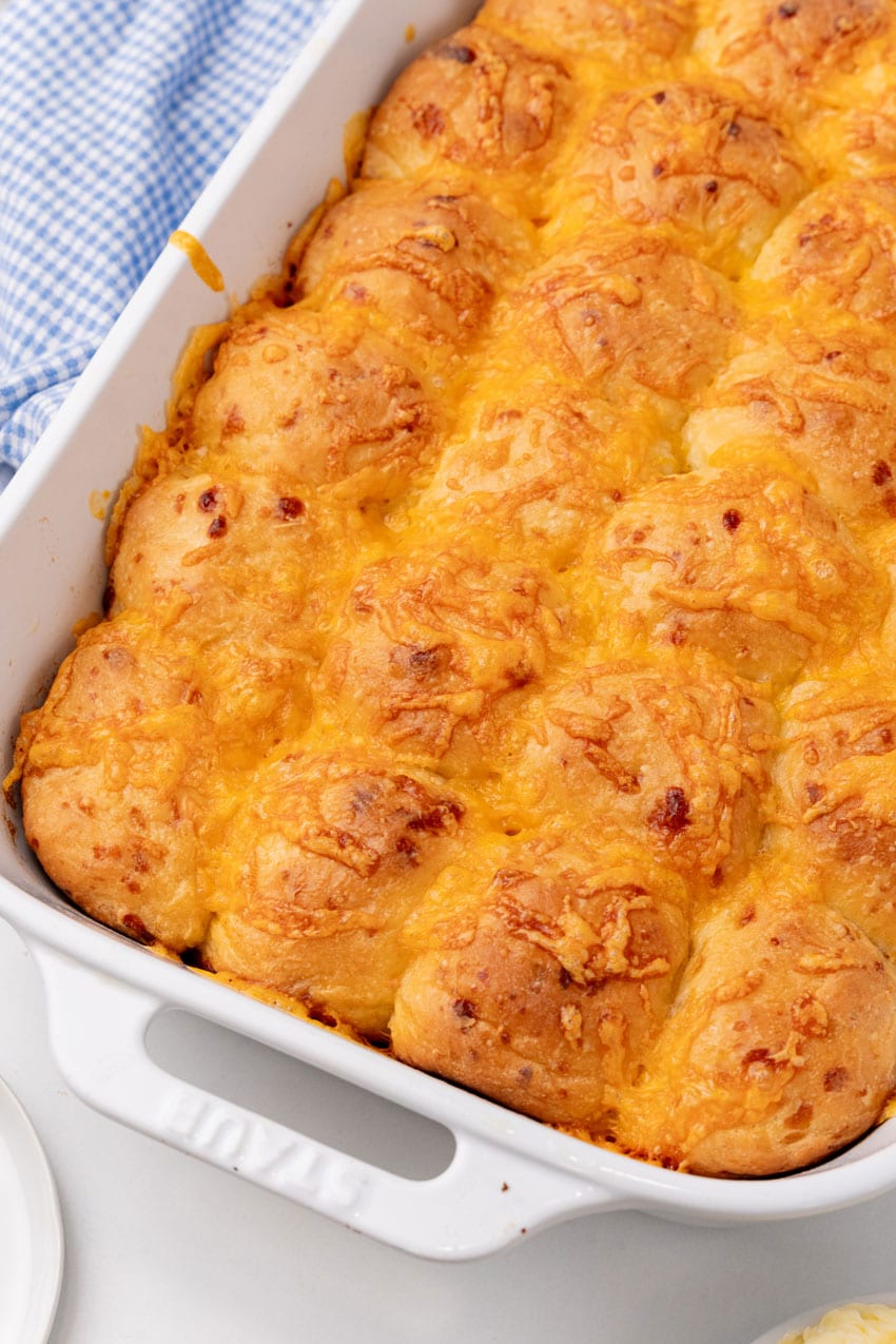 cheesy baked pull apart potato rolls in a white casserole dish