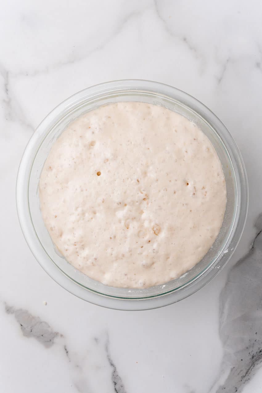 risen bread dough in a glass mixing bowl