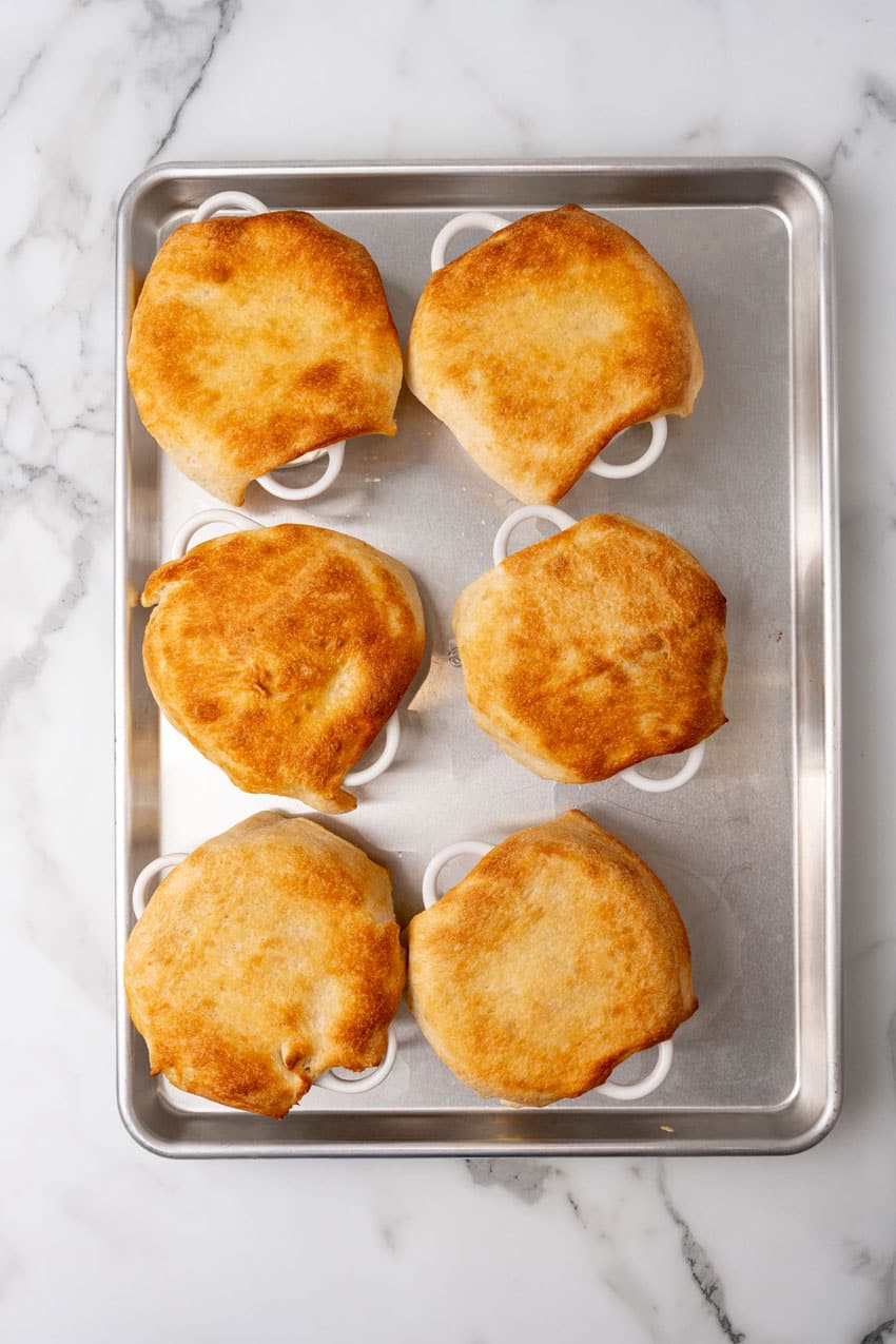 baked pizza pot pies arranged in two rows on a rimmed baking sheet