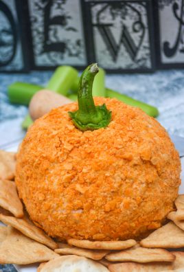 PUMPKIN SHAPED TEX MEX CHEESE BALL RESTING ON WHEAT CREACKERS ON A WHITE SERVING PLATTER