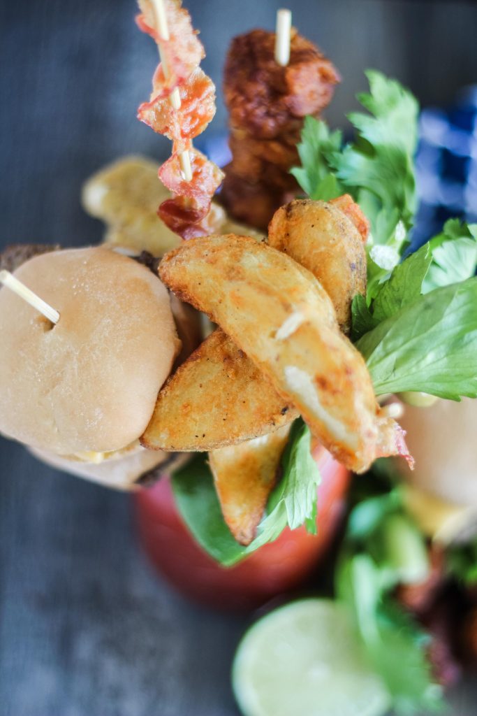 ultimate bloody mary in a Mason jar with a variety of skewered appetizers for garnish