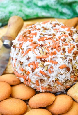 a carrot cake cheese ball on a wooden cutting board surrounded by cookies