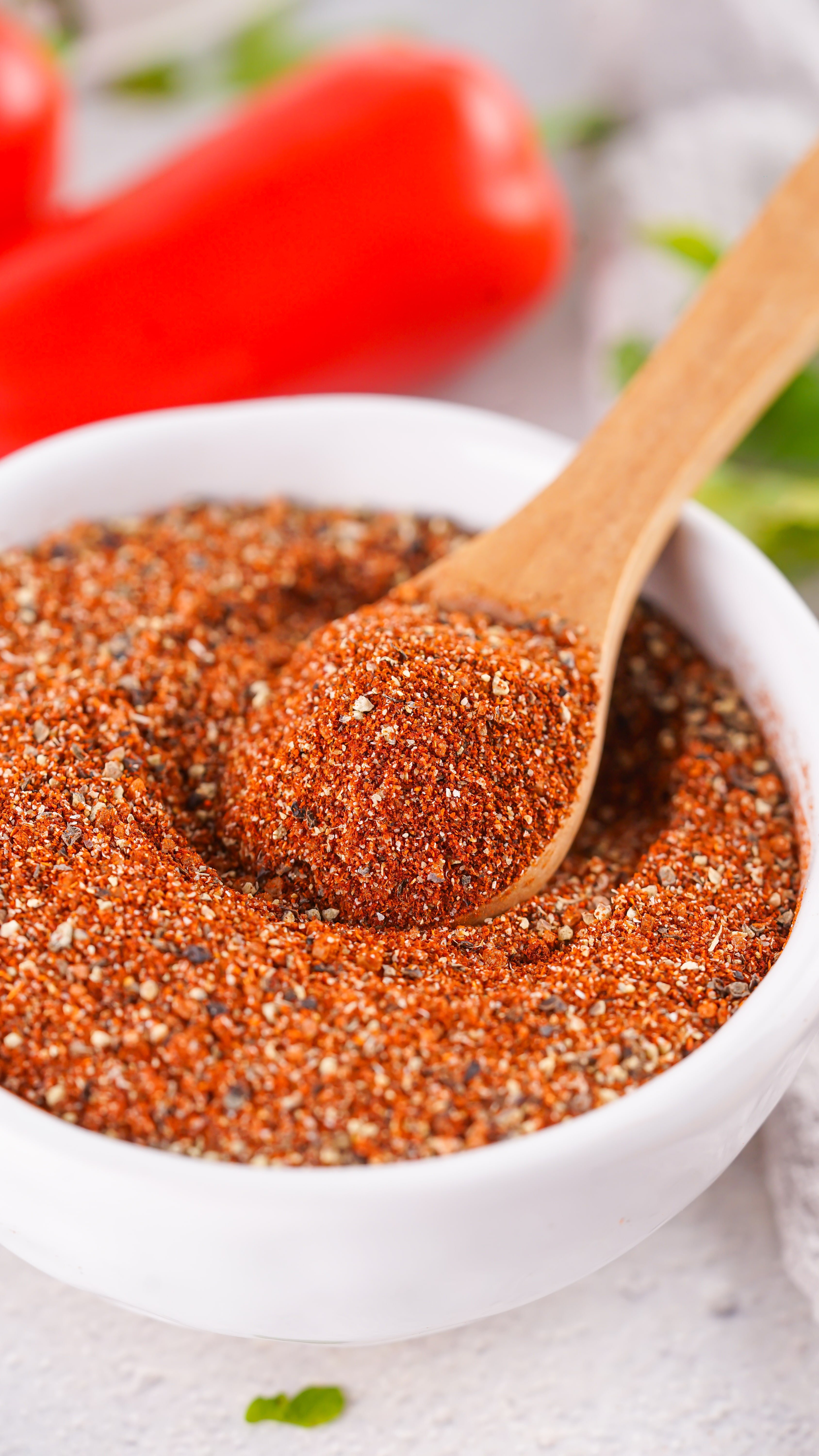 a wooden spoon scooping homemade barbecue rub out of a small white prep bowl