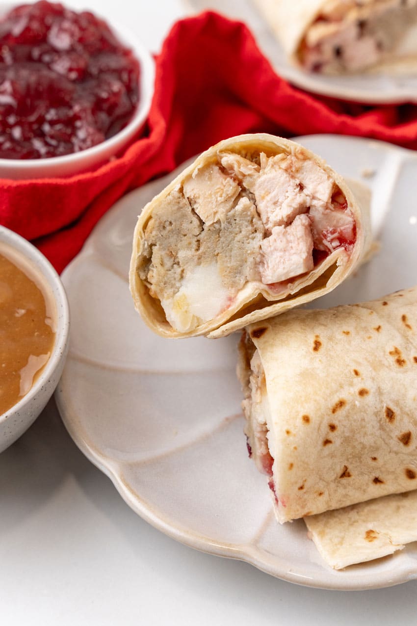 two halves of a leftover turkey burrito on a white plate