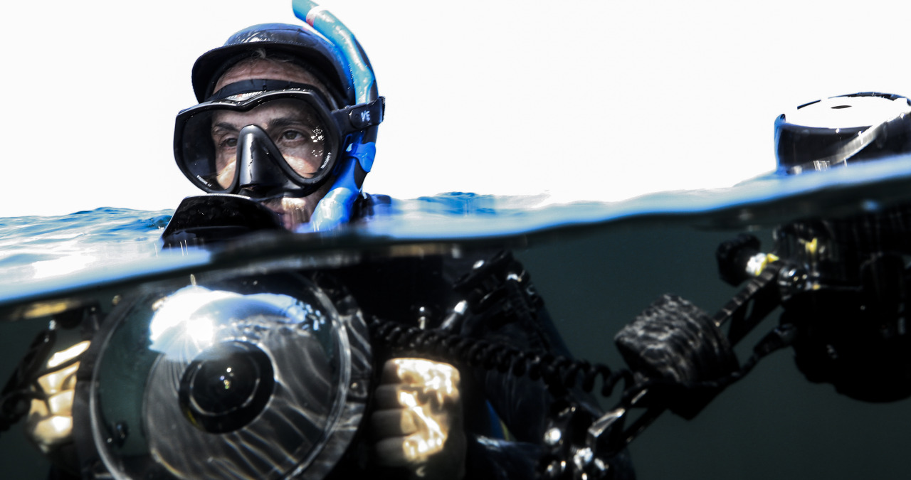 Underwater photographer with camera half out of the water.