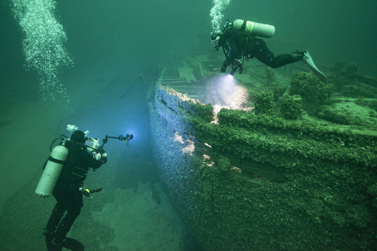 Two divers swim near a shipwreck at the bottom of Lake Ontartio.