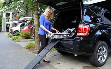 Lady in blue shirt removes Stair-Trac from the trunk of her van