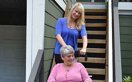 Senior in a wheelchair and a pink shirt goes up the stairs using Stair-Trac