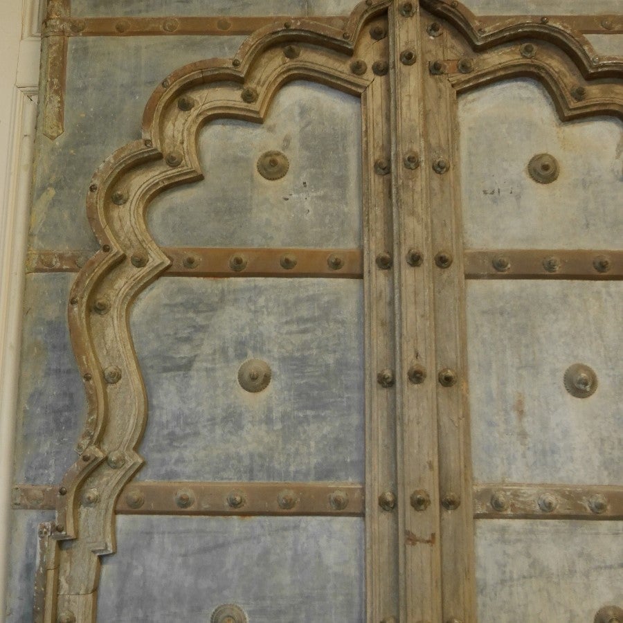 Pair of mid-19th century Mughal arched teak doors, nice color to the faded zinc panels and weathered teak wood surrounds, decorated with original worn brass studs.