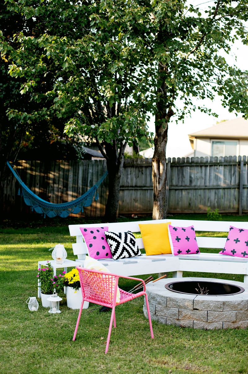 the finished bench with pillows on it around a fire pit