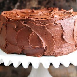 Amazing chocolate cake photographed with rich chocolate buttercream frosting on a white cake stand // addapinch.com