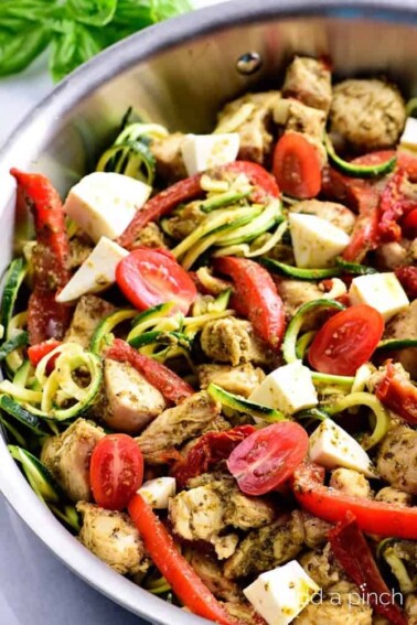 Stainless pan with pesto chicken and fresh vegetables.