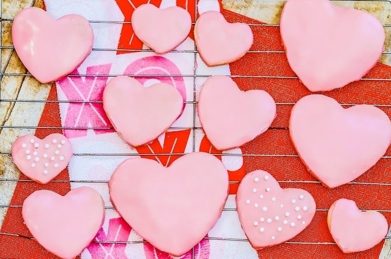 A cooling rack full of pink sugar cookies.