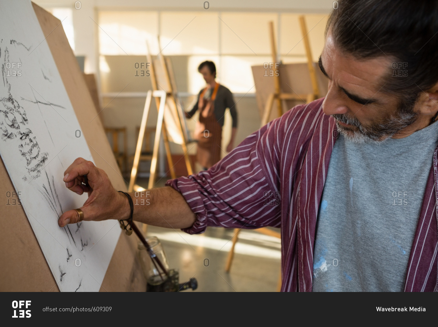 Close up of man sketching on paper in art class