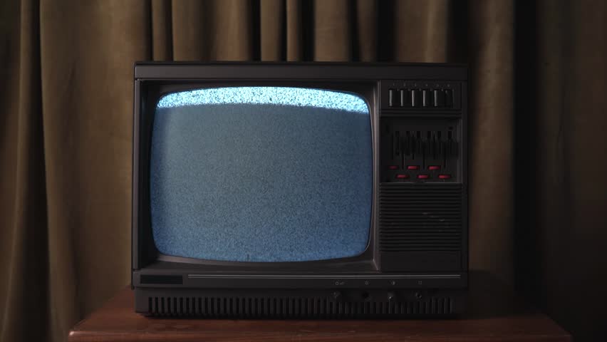 Old 80's retro television with bad signal, tv showing only static with a curtain background in the evening or at night time