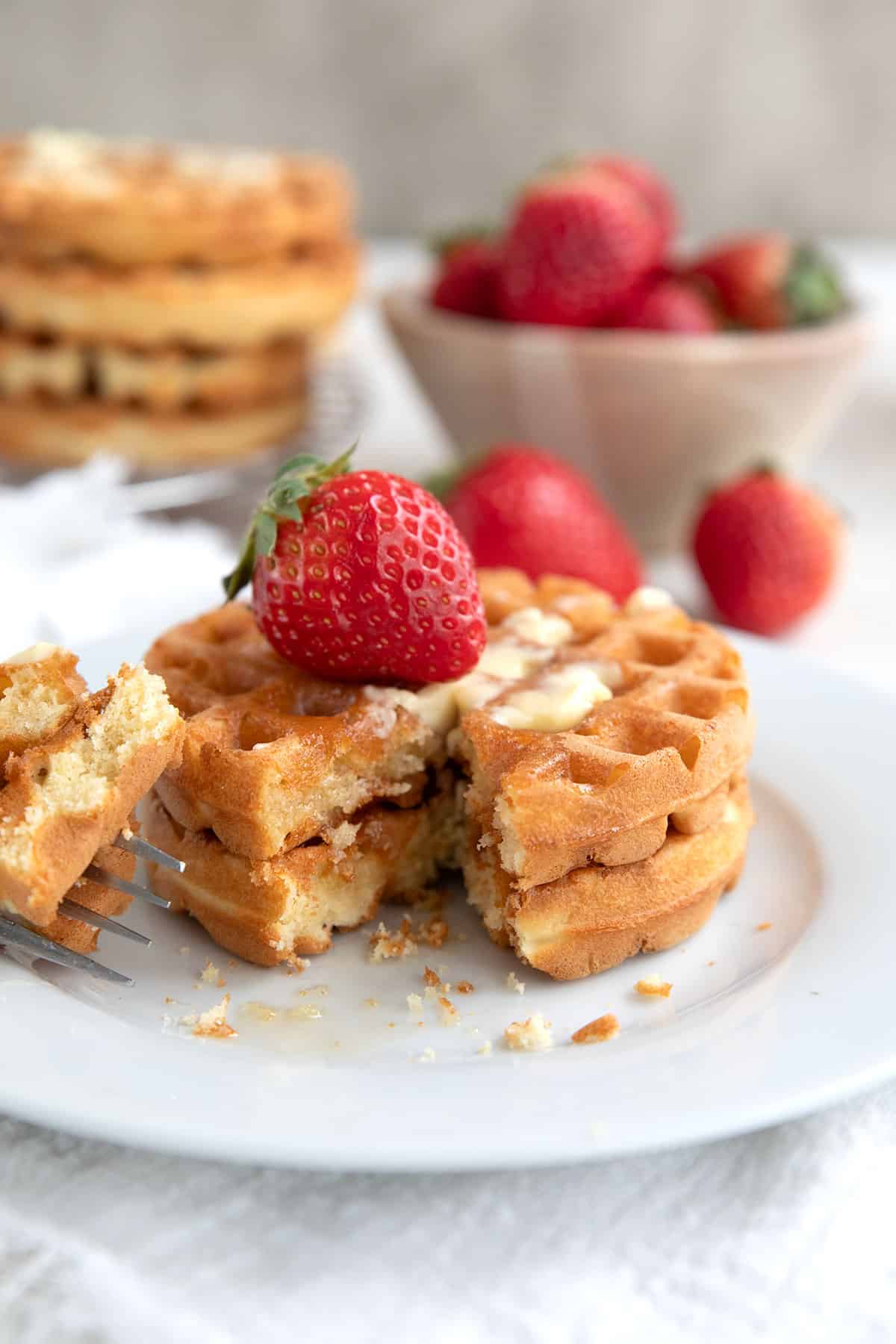 Two keto waffles on a white plate with a forkful taken out of them.