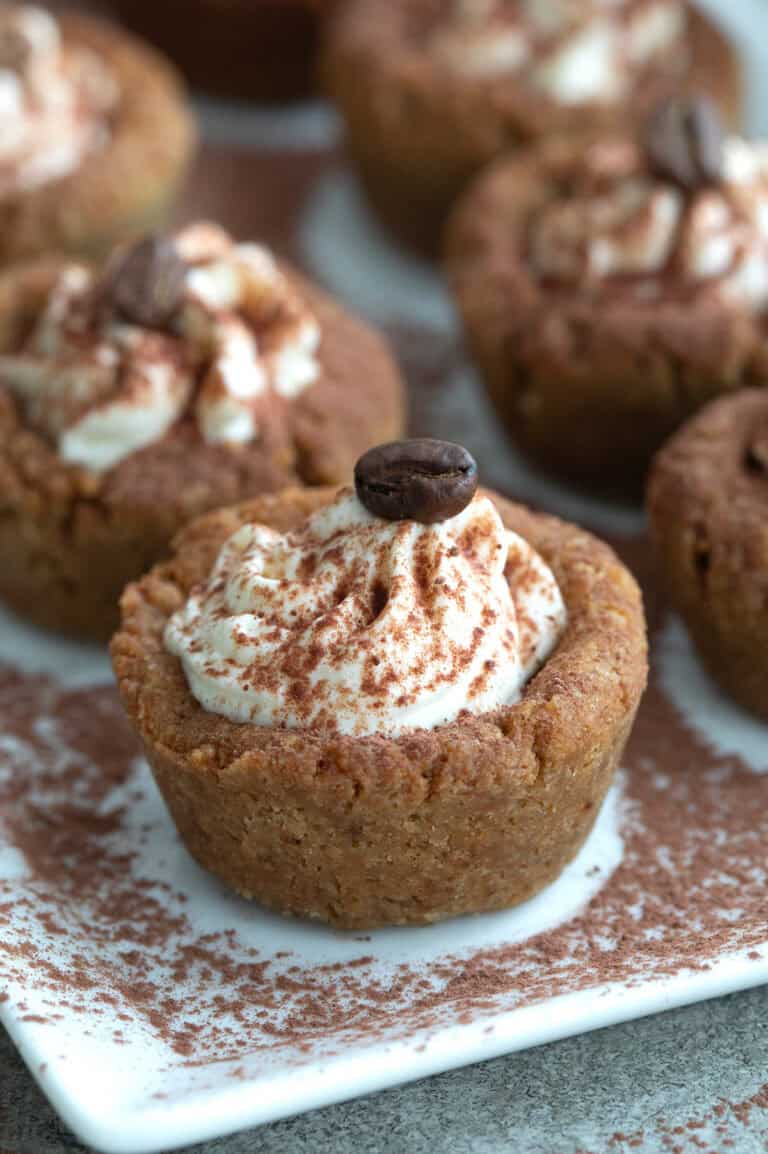 Close up shot of Keto Tiramisu Cookie Cups on a white platter, sprinkled with cocoa powder.