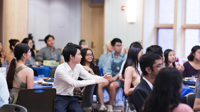 Students sitting at tables in a room, smiling