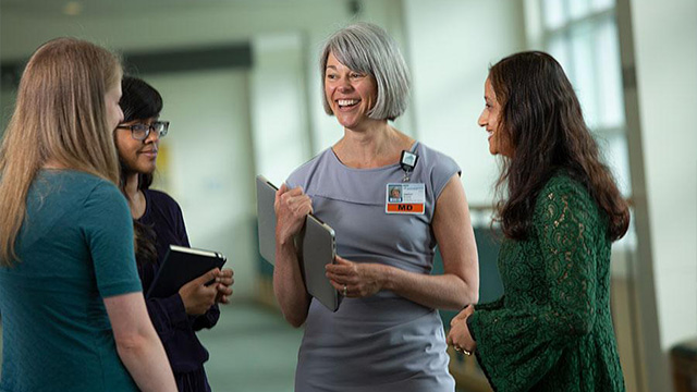 A group of women standing in a hallway speaking to each other.