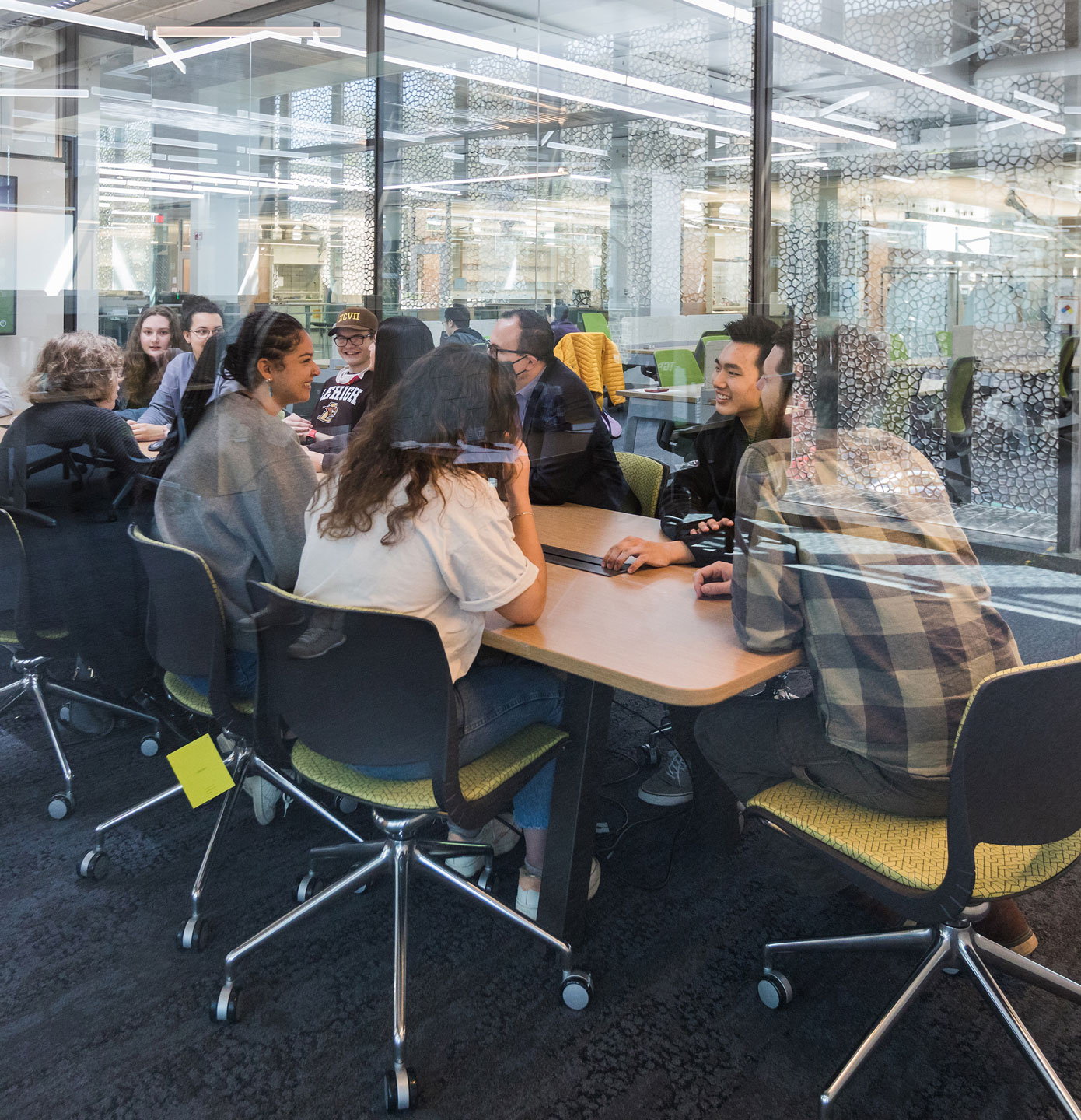 Students gathered around a conference room table, engaged in a discussion