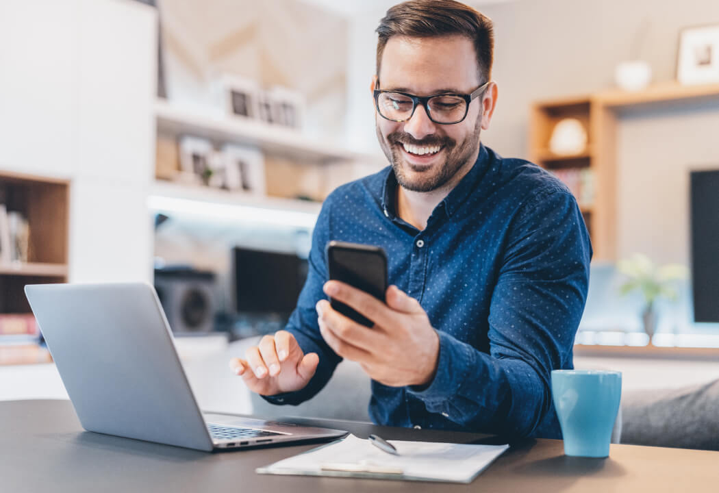 Man using a smartphone and a laptop