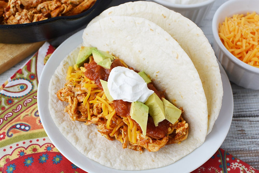 Chicken ranch taco in a tortilla with toppings on a plate.